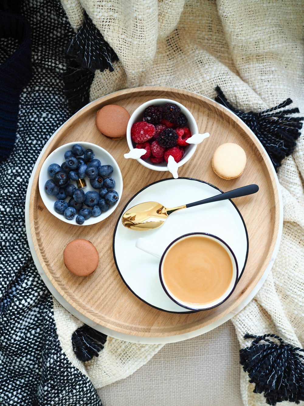 Photographie à plat de tasse de café à côté des framboises et des myrtilles sur des bols