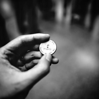 grayscale photography of person holding coin