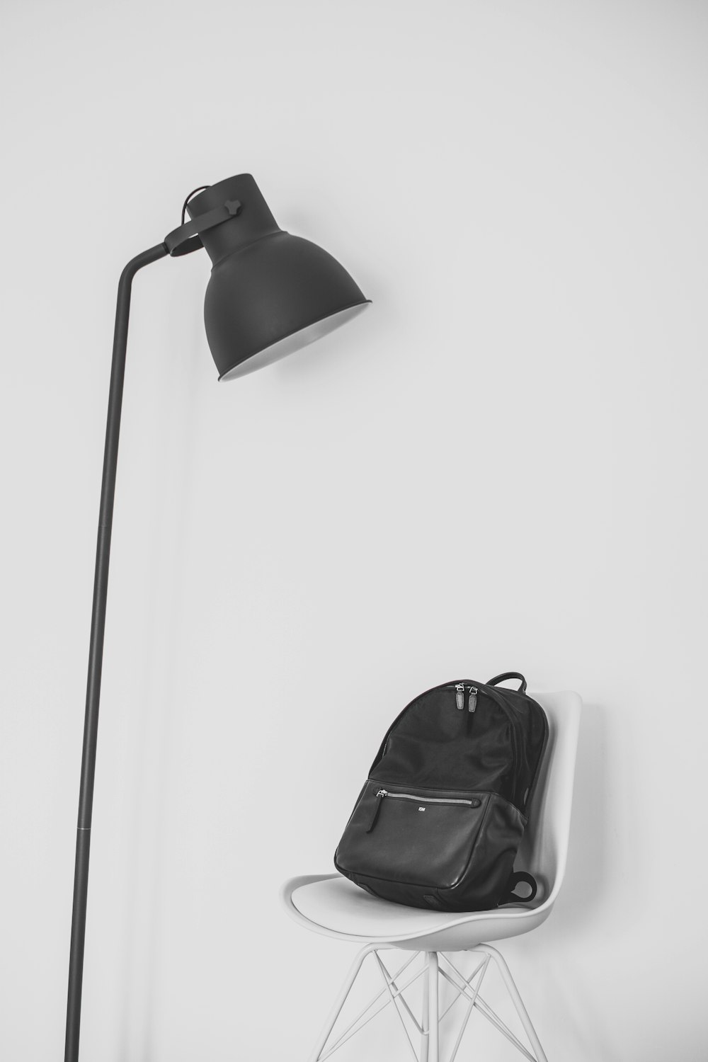lampe noire à côté du sac à dos sur le dessus de la chaise