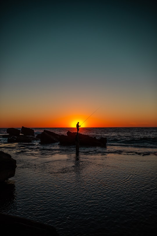 silhouette of man holding fishing rod in Palm Beach Australia