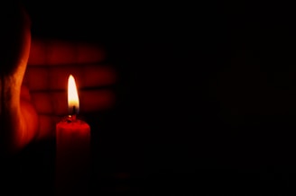 Close-up of a woman’s hand gently holding a glowing flame, representing transformation and strength.