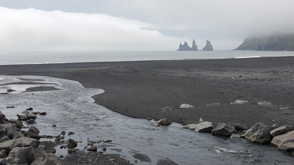 gray sand near shore under cloudy sky during daytime