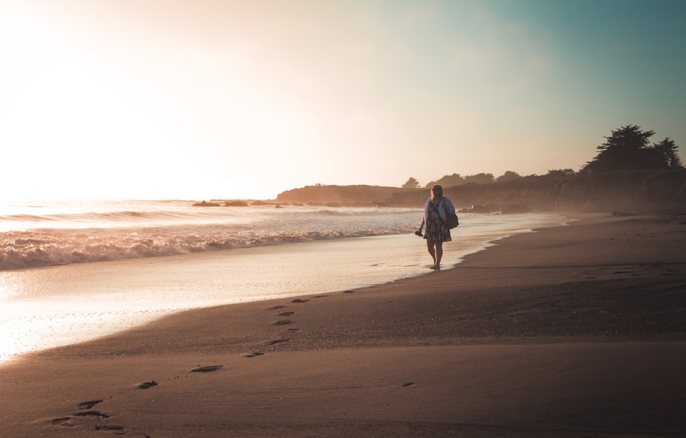 woman walking along the beach during daytime