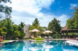 resort with pool, hut, and patio umbrellas