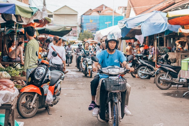 Locals riding scooters through a busy street market in Da Nang, Vietnam