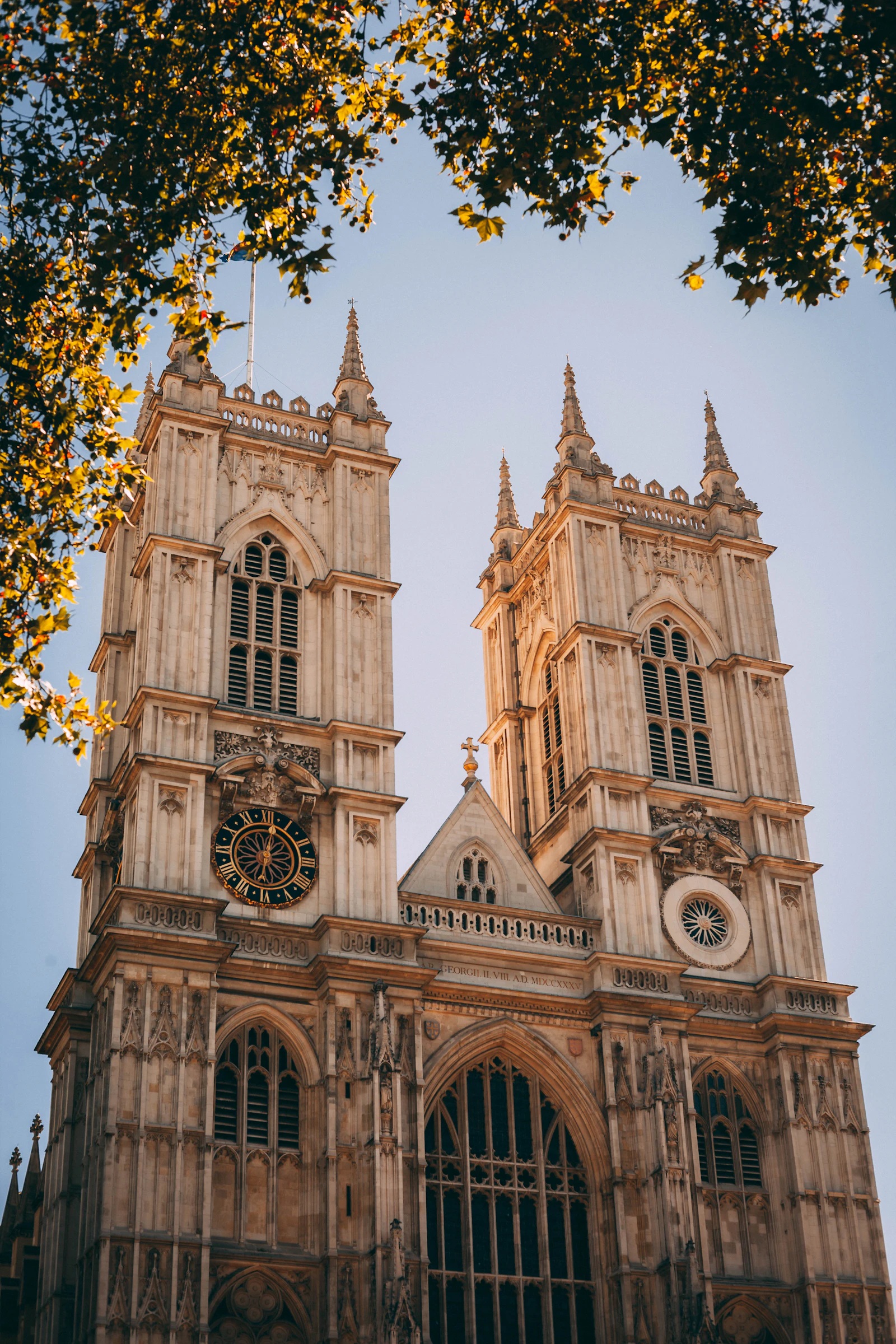 Travel photograph: The twin towers and carved west front of Westminster Abbey framed by autumn leaves.