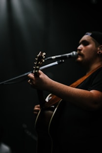 person playing guitar while singing