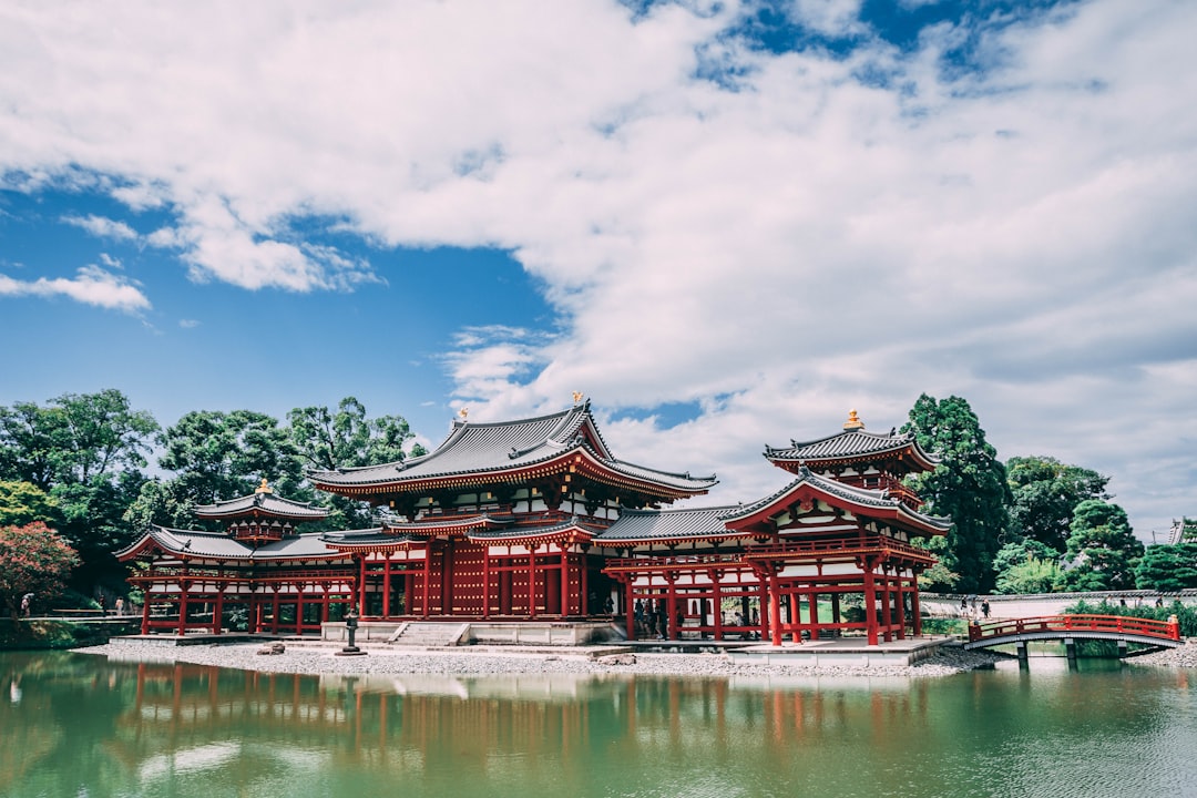 pagoda temple across body of water under blue cloudy sky,