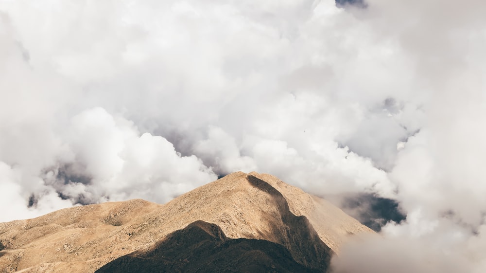 brown mountain top under while clouds