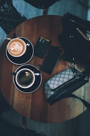 A stylish canvas tote bag with leather handles resting on a wooden table beside a coffee cup.