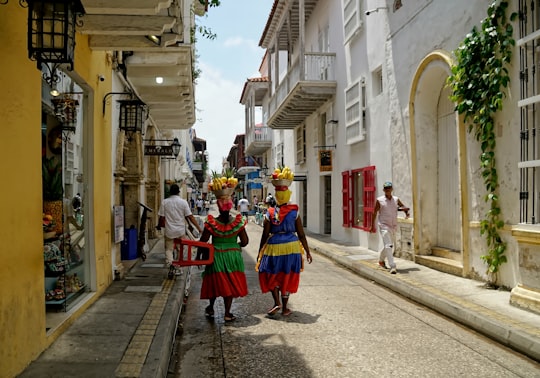 people walking on road between concrete houses during daytime in Cartagena Colombia