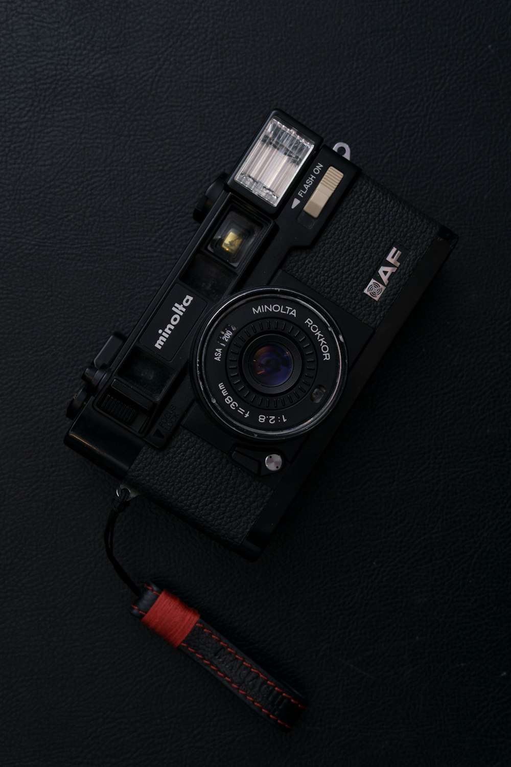 black Minolta AF point-and-shoot camera on black surface