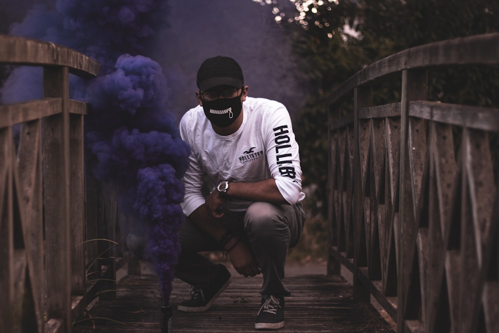 man with black mask standing on bridge