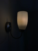A modern wall sconce with a sleek design illuminating a hallway.