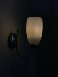 A matte black wall sconce illuminating a modern hallway with subtle elegance.