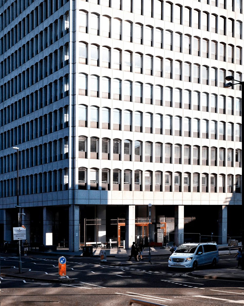 personnes marchant à côté d’un bâtiment en béton