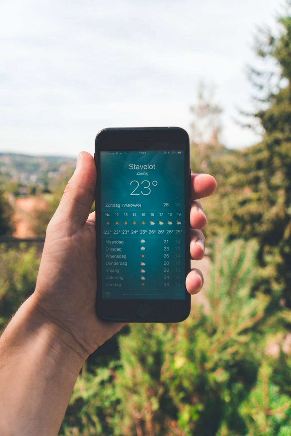 person holding iPhone 7 displaying 23 degree celcius