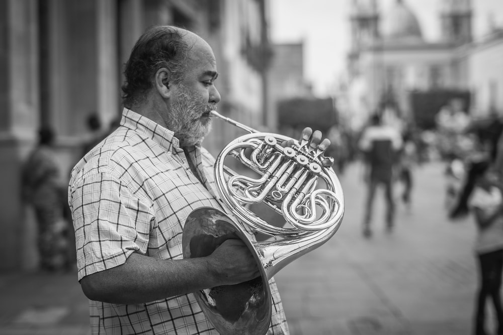 grayscale photography of man playing French horn