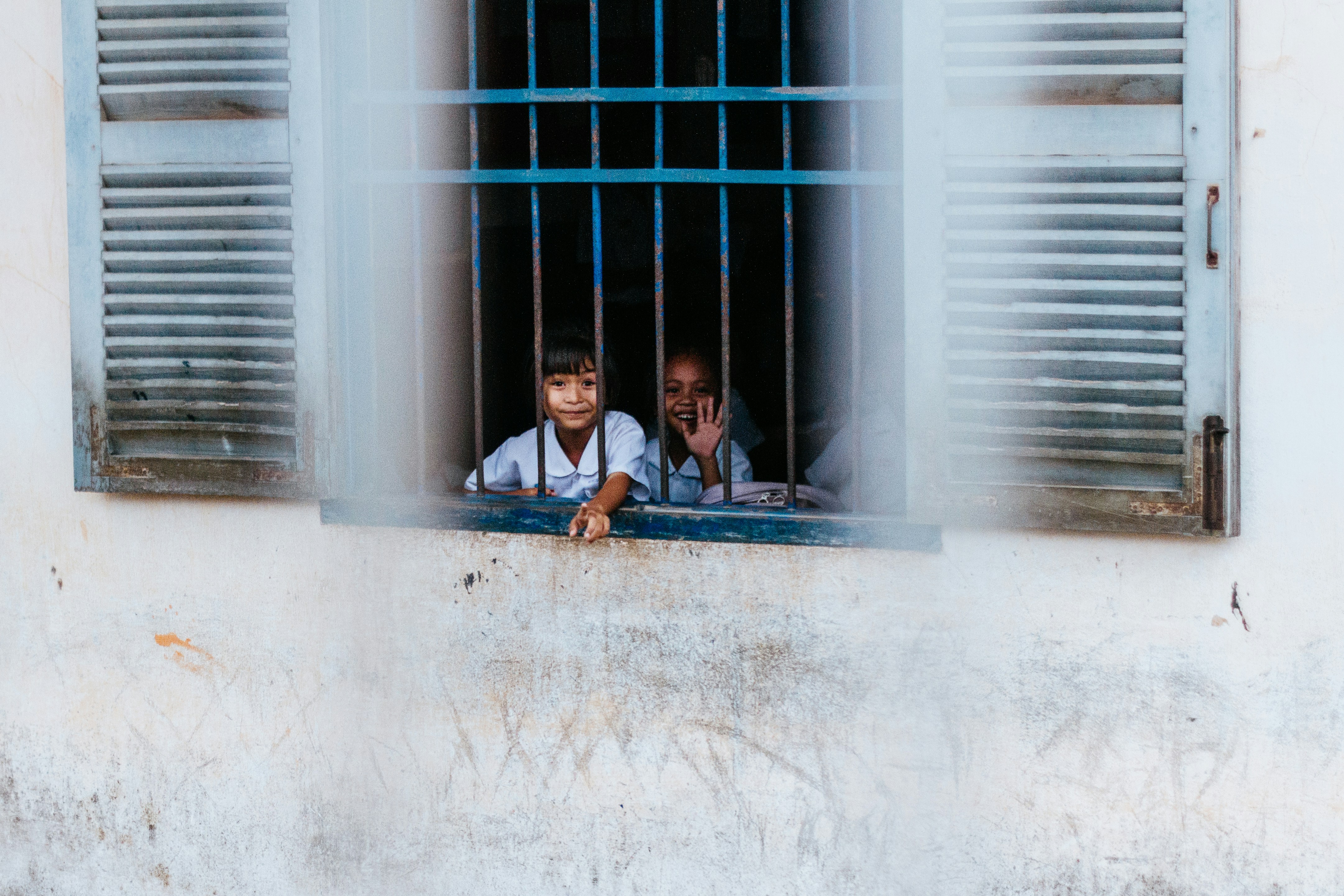 kids sitting near blue window grills