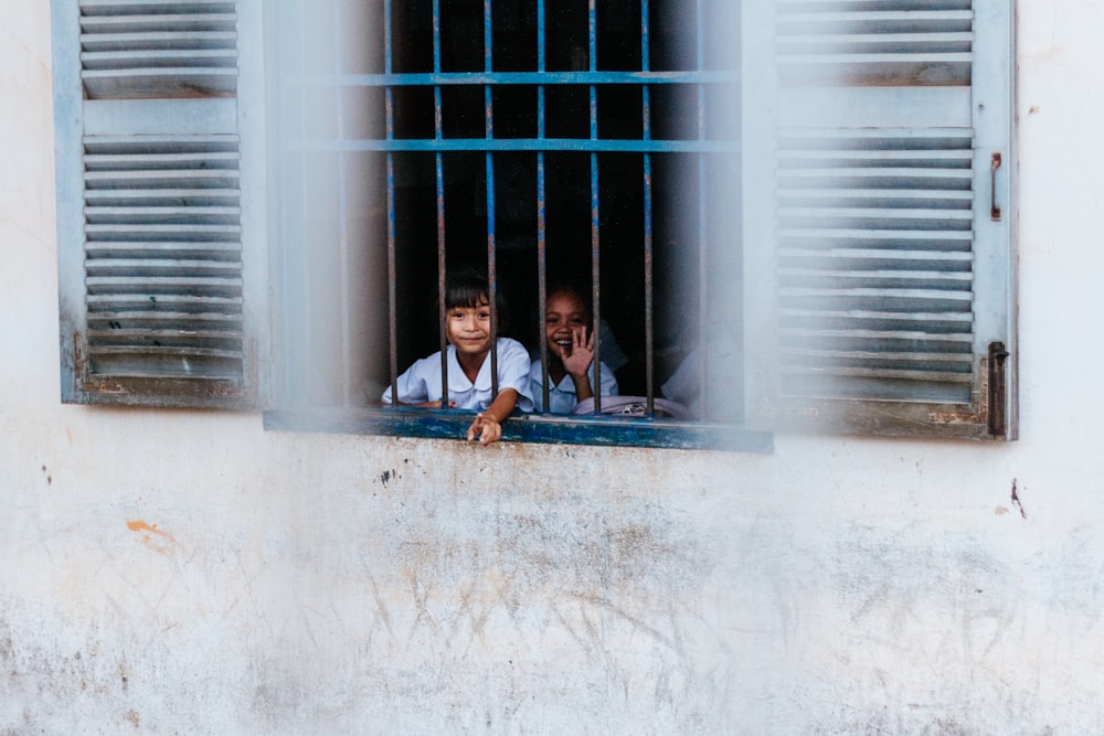 kids sitting near blue window grills