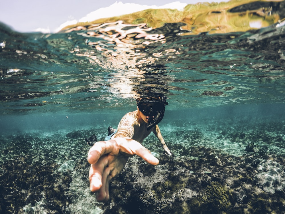 photographie sous-marine d’un homme portant un tuba prêtant la main