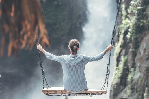 woman sitting on swing near waterfall