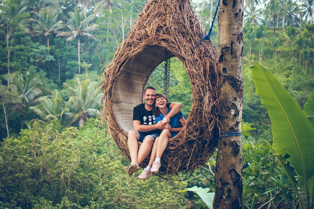 Mann und Frau reiten auf brauner Hängematte neben braunem Baum