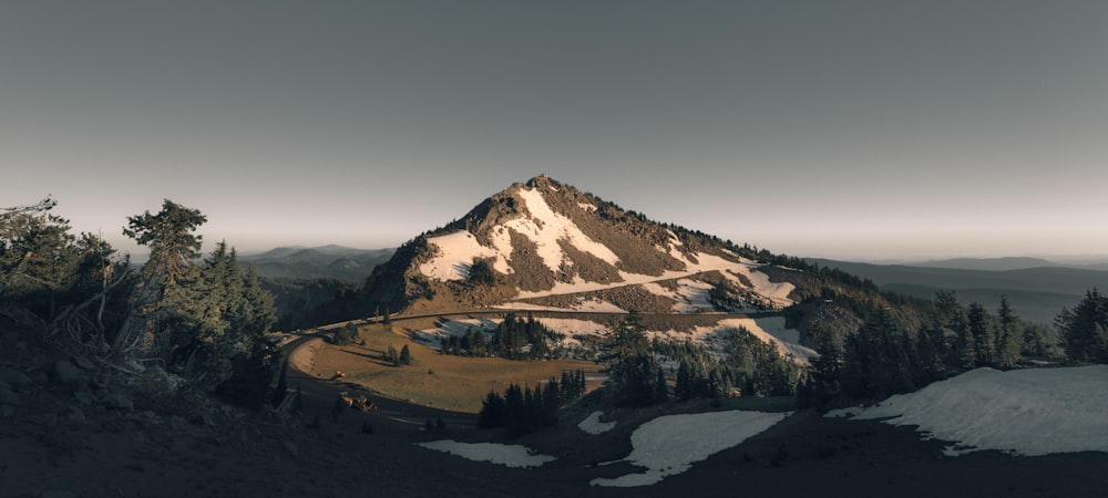 Berg in der Nähe von Bäumen unter grauem Himmel während des Tages