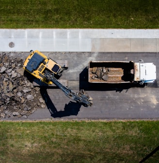 aerial photography of yellow heavy equipment beside white dump truck at daytime