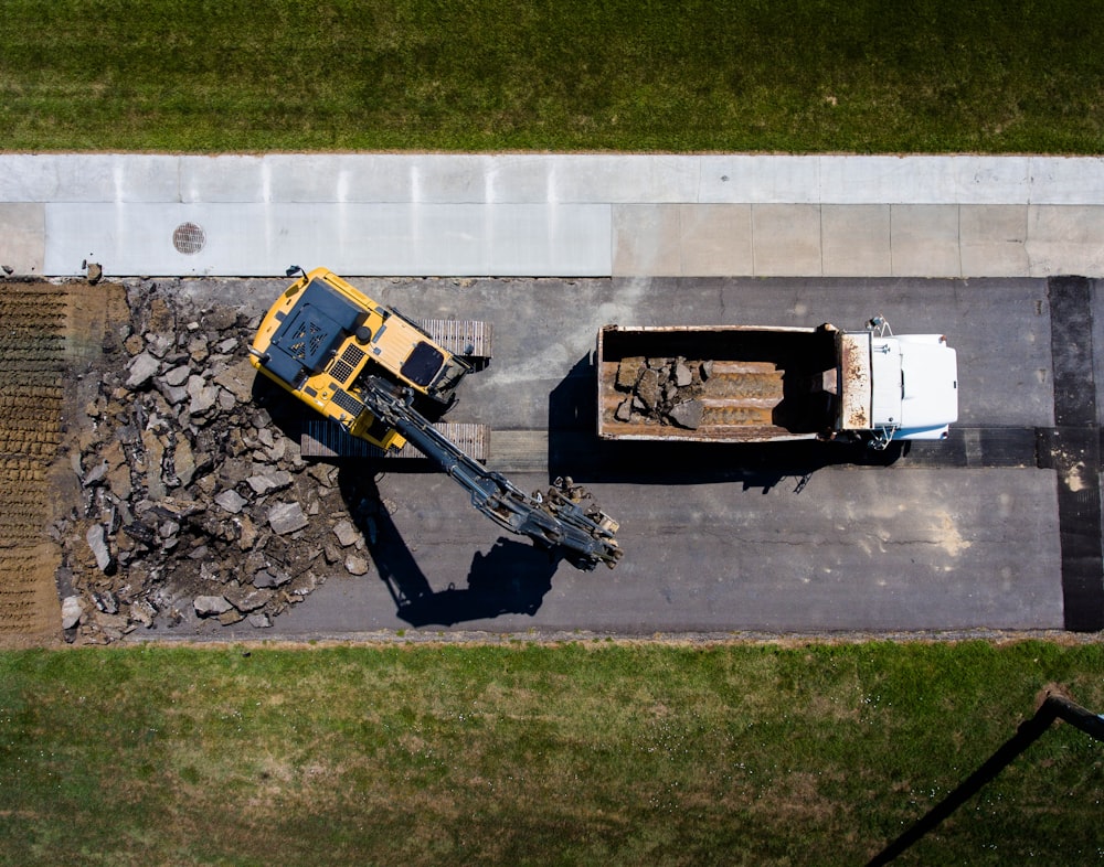 Fotografía aérea de equipo pesado amarillo junto a camión volquete blanco durante el día