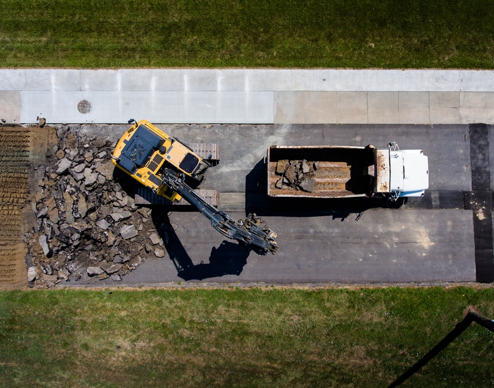 aerial photography of yellow heavy equipment beside white dump truck at daytime