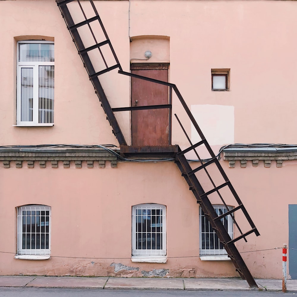 Casa de 2 andares pintada de bege com escada de emergência de aço preto