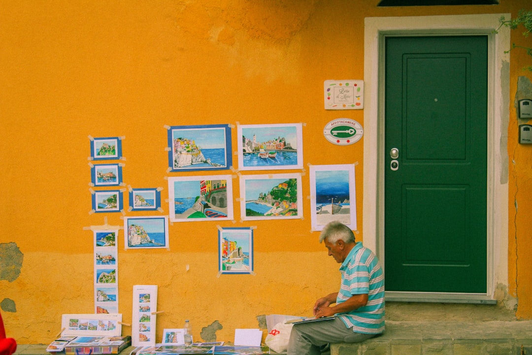 man near closed green window with paintings,