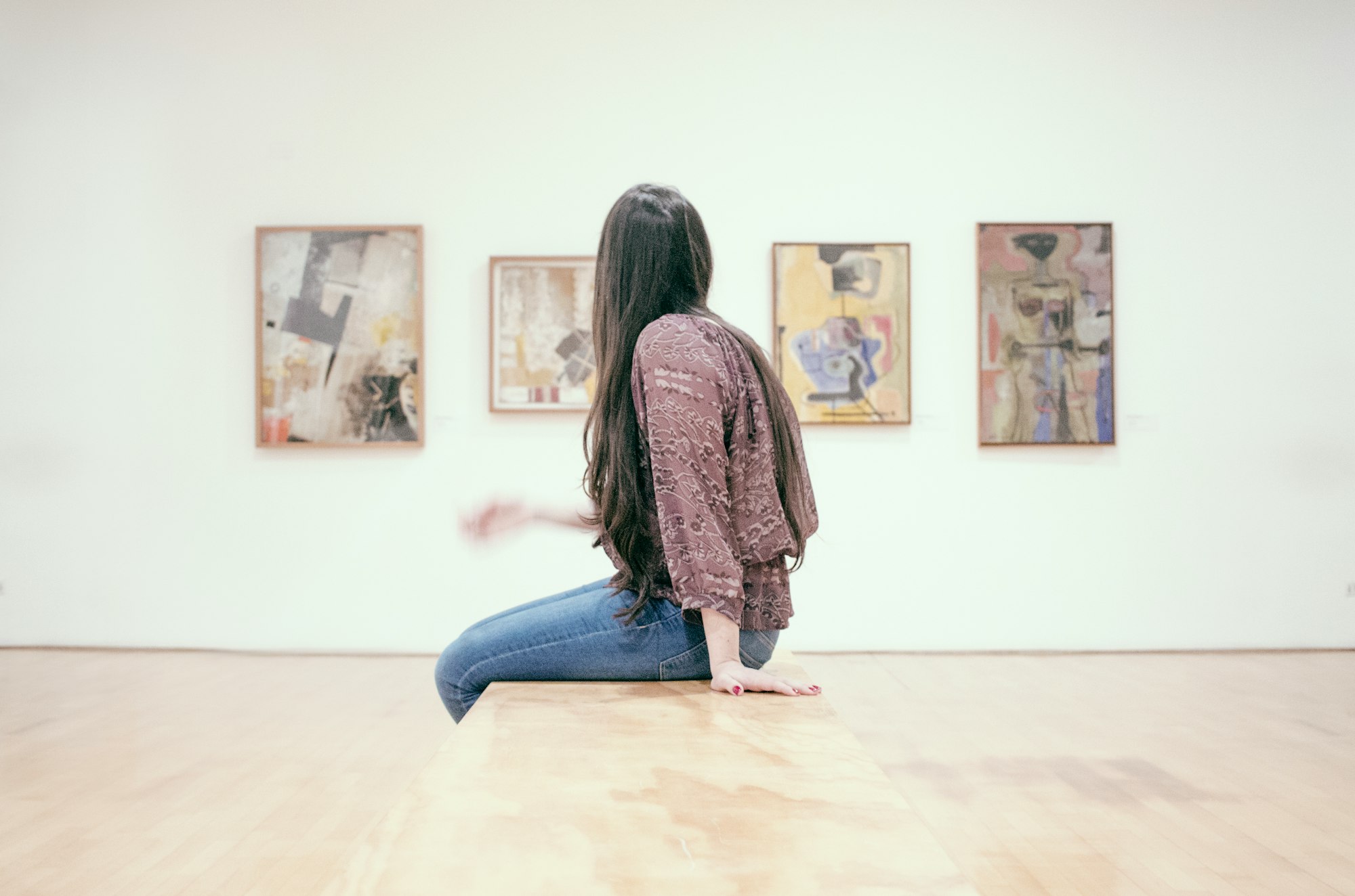 a visitor in an art gallery viewing four paintings on a wall