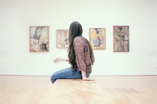 a visitor in an art gallery viewing four paintings on a wall