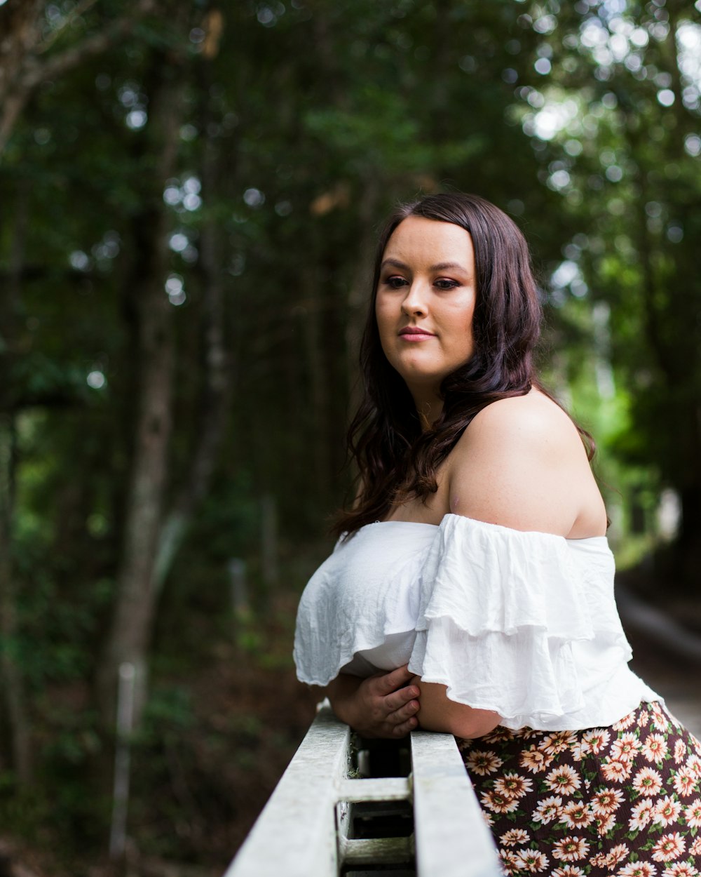 woman in white off-shoulder top leaning on bridge