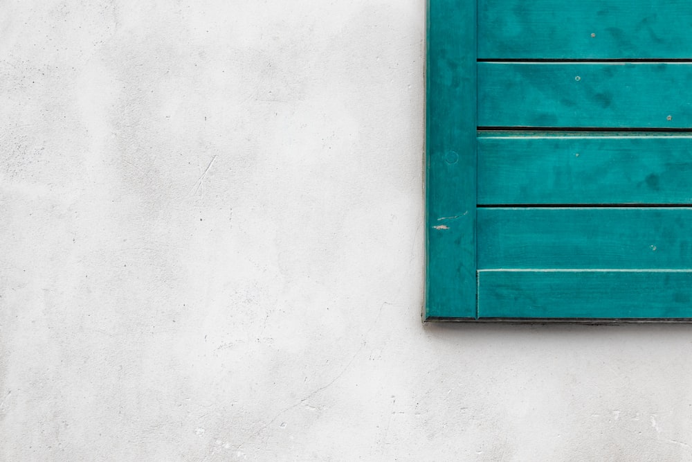 a green shutter on a white stucco wall