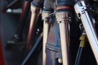 Close-up view of metallic pipes and connectors, possibly part of a machine or engine. The components are polished and reflect light, highlighting their sleek industrial design.