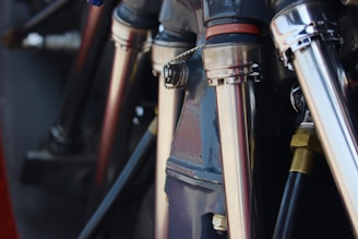 Close-up view of metallic pipes and connectors, possibly part of a machine or engine. The components are polished and reflect light, highlighting their sleek industrial design.