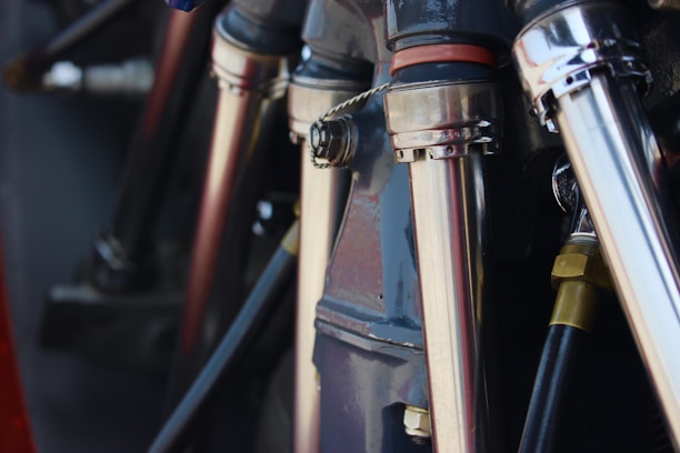 Close-up view of metallic pipes and connectors, possibly part of a machine or engine. The components are polished and reflect light, highlighting their sleek industrial design.