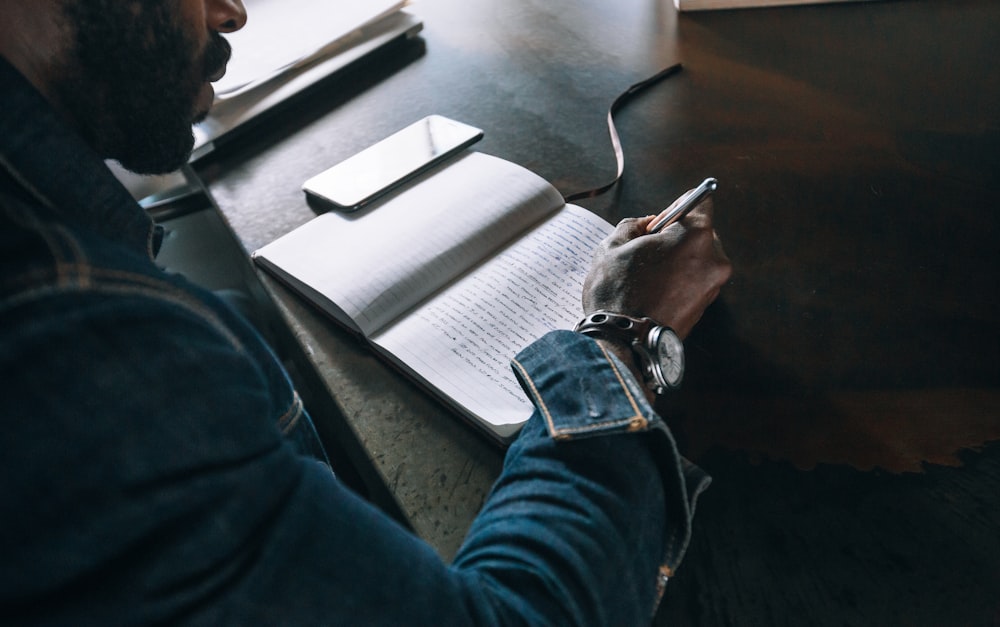 person holding pen on notebook