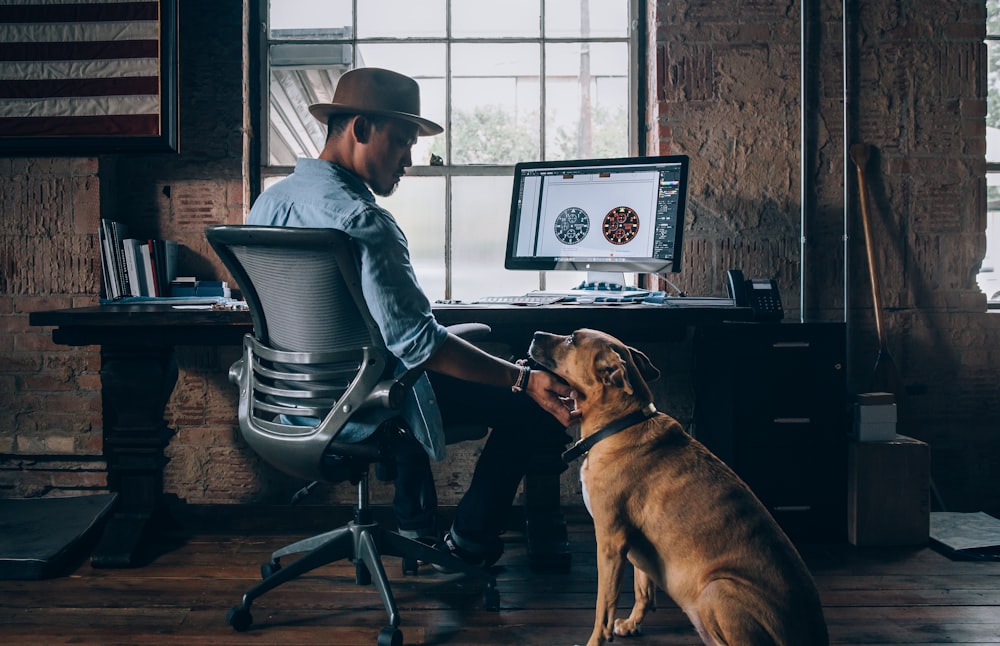 man sitting on rolling chair holding dog