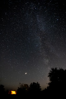 A starry night sky above the peaceful camping area with silhouetted pods
