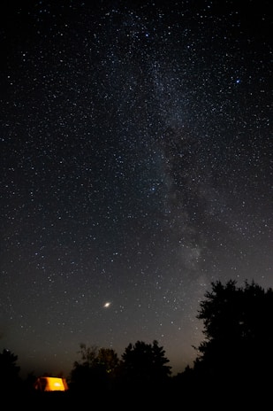 Night sky filled with stars above a quiet campsite in the Indonesian wilderness.