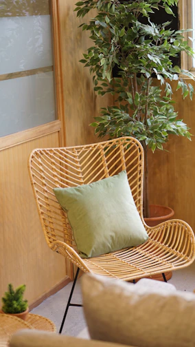 A cozy wicker chair nestled beside a sunlit window with green plants around