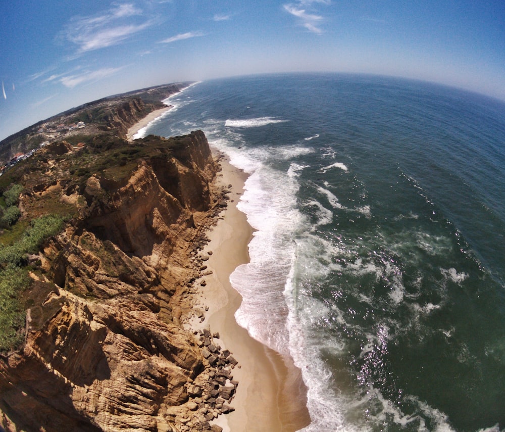 aerial photography of seashore beside cliff at daytime