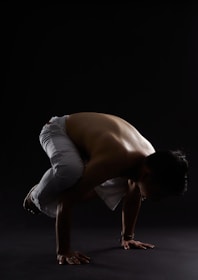 Close-up of a man holding a planche position, muscles flexed, with a dark urban setting.