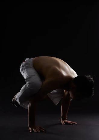 An influencer demonstrating a challenging workout move with perfect form against a dark, minimalist background.