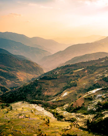 Sunrise over terraced fields in the Uttrakhand hills, with farmers tending to crops.