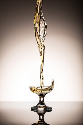 liquid pouring on clear short-stem wine glass